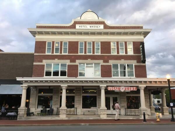 Three-story brick Hotel Massey facade houses ground-floor shops; a man stands near a storefront under a bicycle shop sign, cloudy evening sky above.

Transcribed text: "HOTEL MASSEY"; "PHAT TIRE" (with "BIKE SHOP" beneath); "Bike Rentals"; vertical sign "MASSEY".