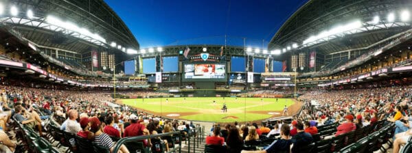 Baseball field hosting a game: a batter at the plate and fielders positioned while a large crowd watches in a brightly lit, roofed stadium with a central video scoreboard.

Visible text (legible): "CHASE FIELD", "DIAMOND CLUB"
