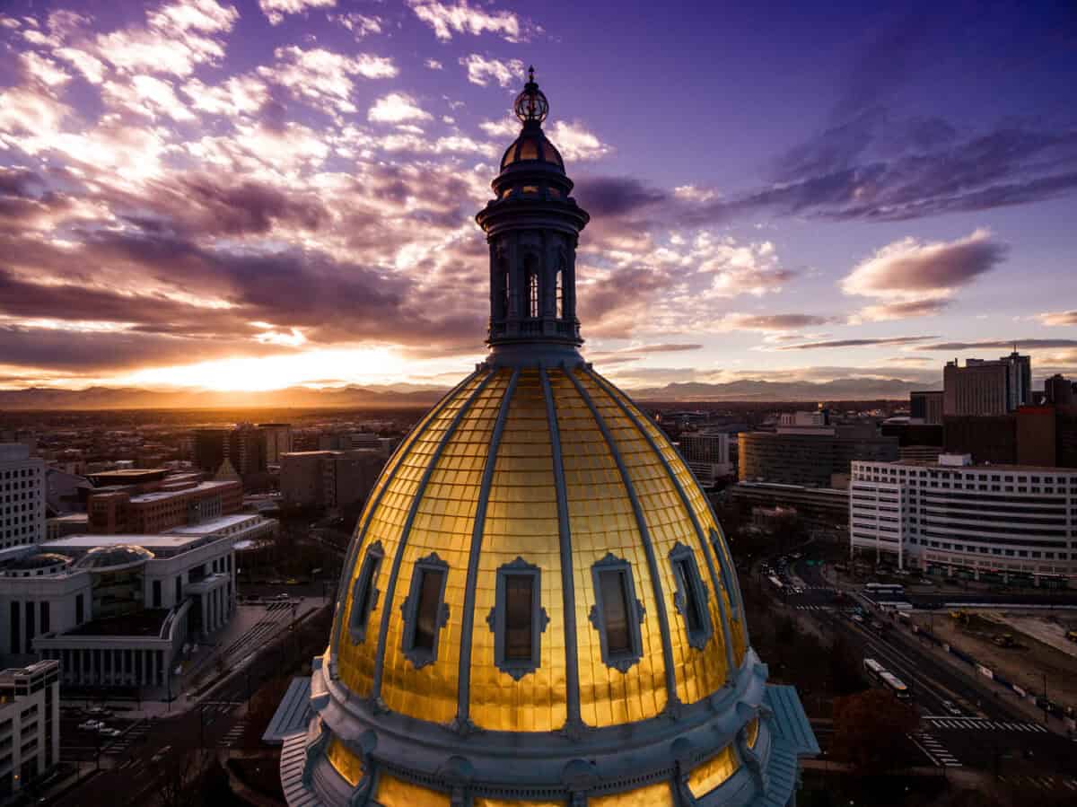 Beautiful drone photograph of a sunset over the golden cupola of the Colorado Capital building in the city of Denver